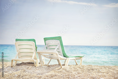 Two sunbeds on tropical beach. Chaise lounges on sea beach. Concept resort vacation. Background of sea beach