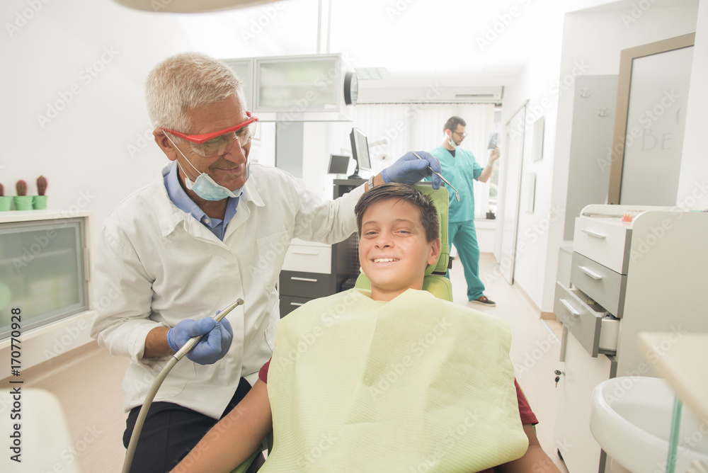 Obraz premium oy with perfect teeth at the dentist doing check up with the clinic at the background - oral hygiene health care concept
