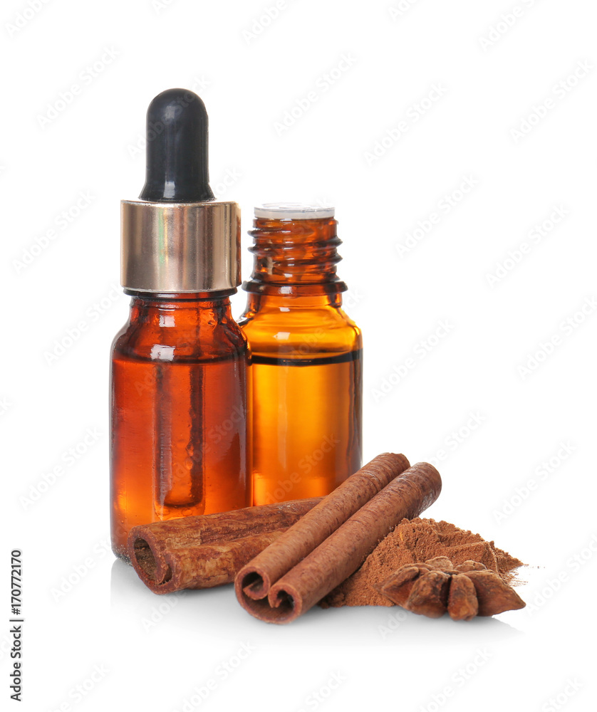 Composition with essential cinnamon oil in glass bottles on white background Composition with essential cinnamon oil in glass bottles on white background