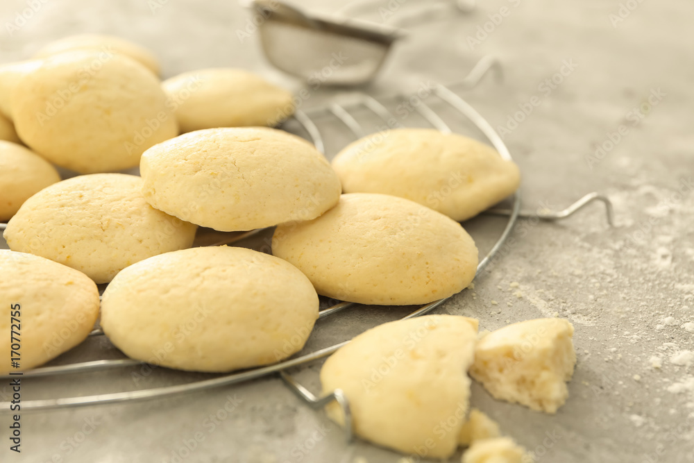 Fototapeta premium Freshly baked soft round cookies cooling on a wire rack with flour dusting and sifter, the cookies have a light golden color and a delicate texture