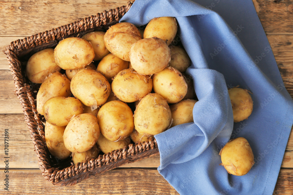 Wicker basket with young potatoes on wooden table Wicker basket with young potatoes on wooden table