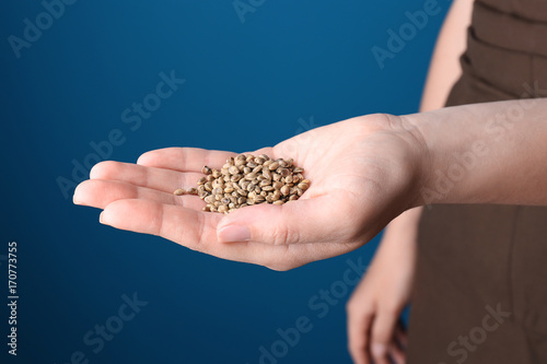 Young woman holding hemp seeds on color background, closeup © Africa Studio