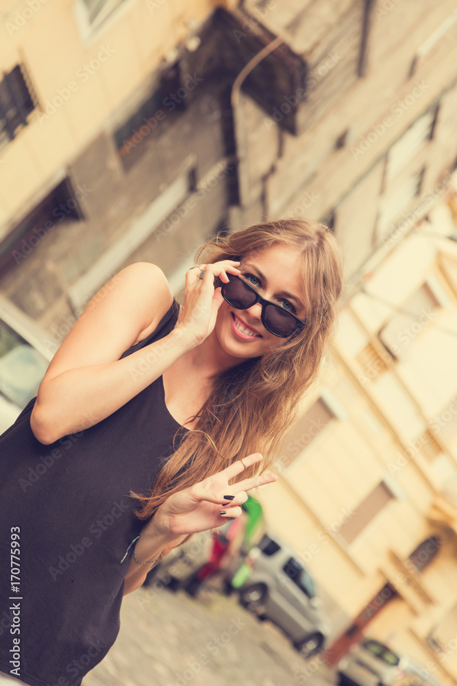 Cute girl posing on the street and having fun while holding peace sign. Cute girl posing on the street and having fun while holding peace sign.