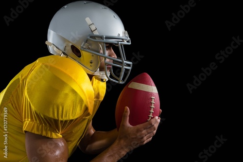 American football player holding a ball close to his face