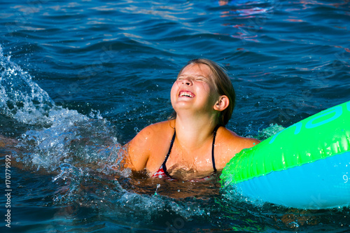  a girl in a colorful swimming wheel smiling and happy while having fun in the water
