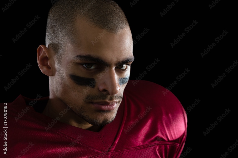 Fototapeta premium Determined American football player against a black background