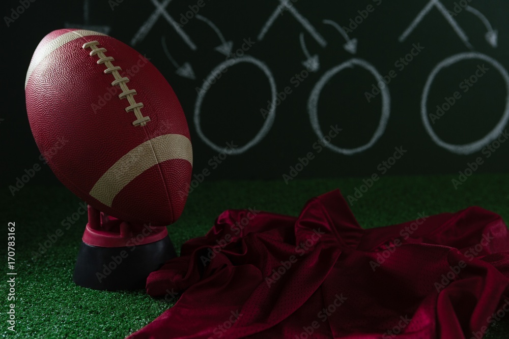 American football jersey and football lying on artificial turf American football jersey and football lying on artificial turf