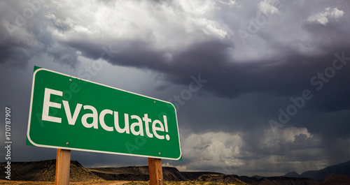 Evacuate Green Road Sign and Stormy Clouds