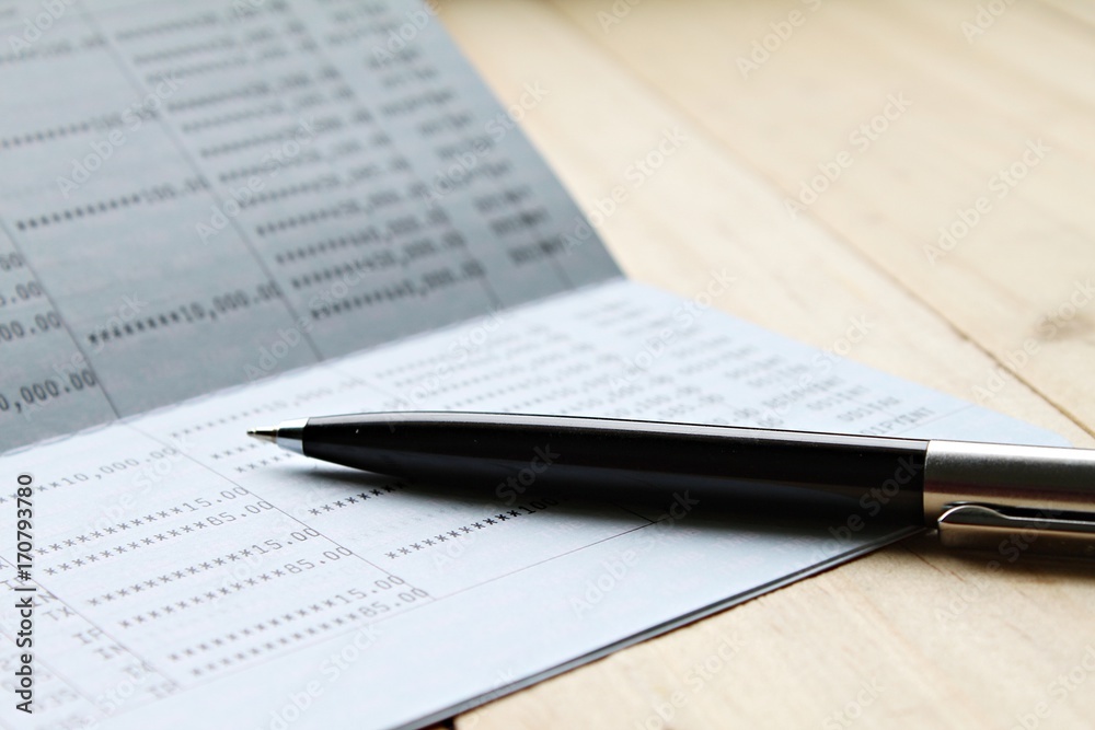 Business, finance, saving money or investment concept : Saving account book or financial statement on desk table Business, finance, saving money or investment concept : Saving account book or financial statement on desk table
