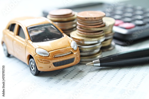 Business, finance, saving money or car loan concept : Miniature car model, coins stack, calculator and saving account book or financial statement on office desk table