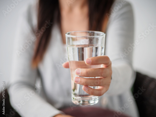 Closeup young woman holding drinking water glass in her hand. Health care concept.