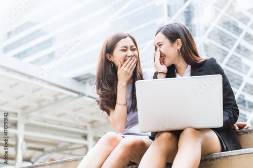 Canvas Print Two female co-workers whispering outside the office (gossip, office, women)