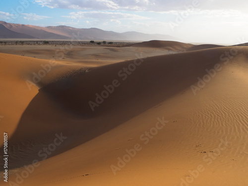 Abstract shape natural rusty red sand dune and salt pan of vast desert landscape background with hot sunlight, Sossus, Namib desert
