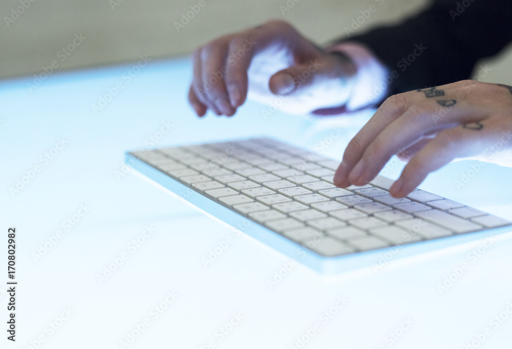 Hands with tattoo typing on a keyboard Hands with tattoo typing on a keyboard