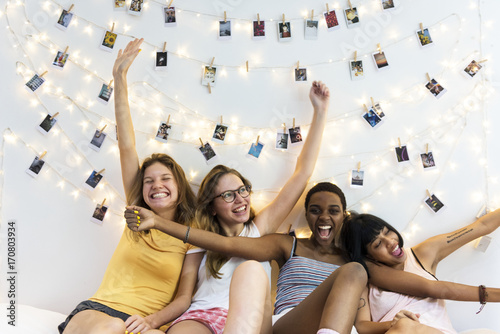Group of diverse women sitting on bed together photo