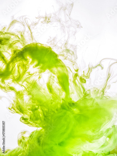 Ink swirl in water isolated on white background. The paint in the water. Soft dissemination a droplets of green ink in water close-up. Abstract background. Soft focus.