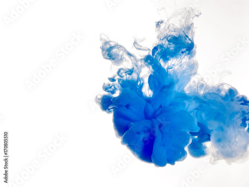 Ink swirl in water isolated on white background. The paint in the water. Soft dissemination a droplets of blue ink in water close-up. Abstract background. Soft focus.