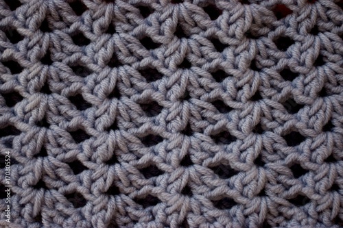 a close-up of a simple beige crochet pattern. Texture of Pink and Gray crochet yarn textile as background. Top view. Vertical direction of threads.