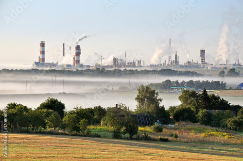Working Nitrogen Plant in smoke in summer morning. Abandoned village in the foreground. Grodno, Belarus.