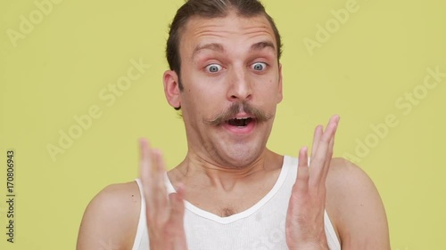 speechless astonished tense man in surprise over yellow background closeup slomo. Concept of emotions