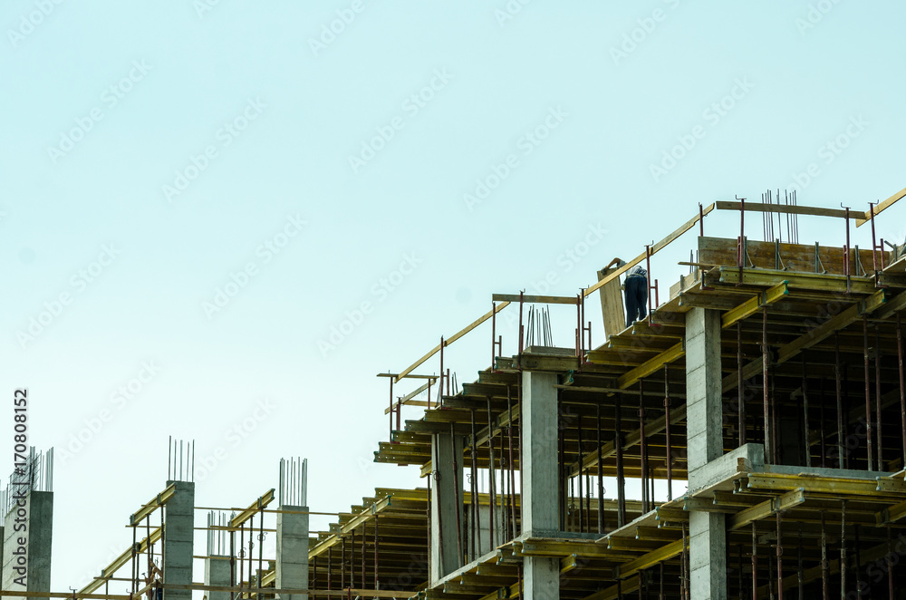 One worker working on the top of the building construction site with scaffold One worker working on the top of the building construction site with scaffold
