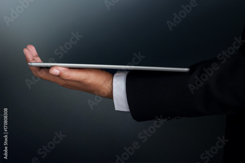 Part of Businessman Hand holding a digital tablet for present modern business work, Side view, Dark tone