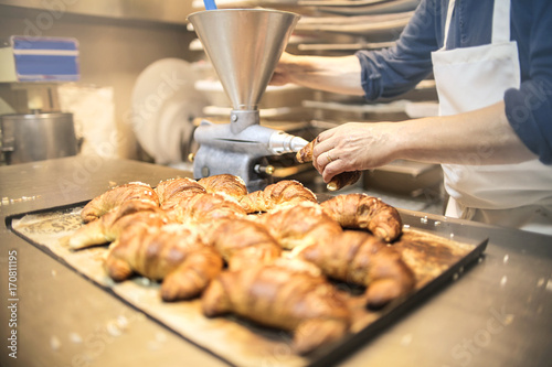 Pastry chef filling croissant with cream