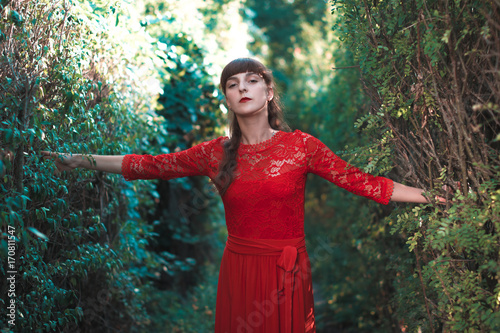 Beautiful young girl in a long red dress in an autumn park. photo