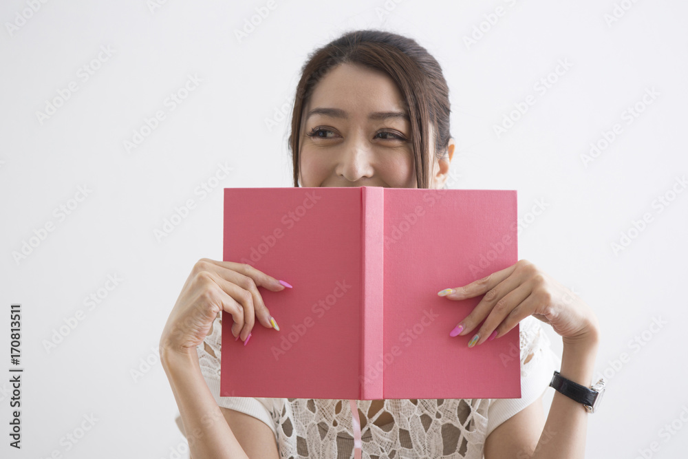 本で顔を隠す女性