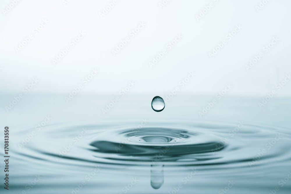 Water drop and splash on water surface on blue background Water drop and splash on water surface on blue background