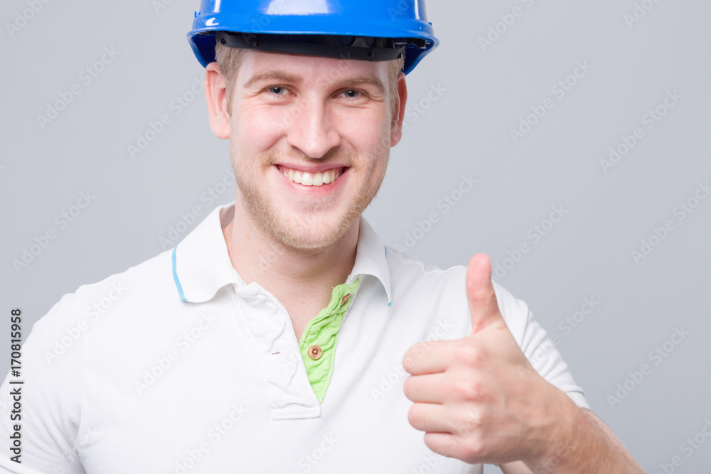 Junger lächelnder Mann mit Helm zeigt Daumen hoch Junger lächelnder Mann mit Helm zeigt Daumen hoch
