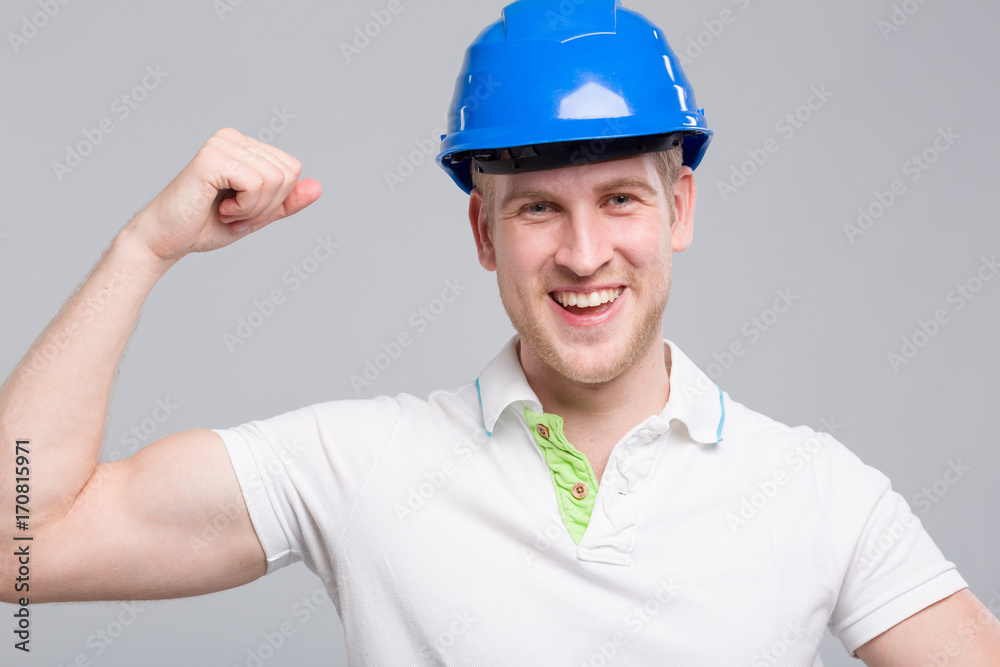 Junger dynamischer Mann mit Helm zeigt Muskeln Junger dynamischer Mann mit Helm zeigt Muskeln