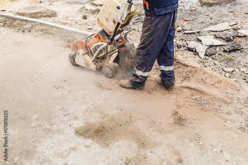 A worker cutting concrete road with diamond saw blade machine