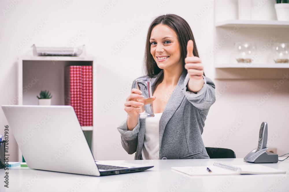 Young businesswoman is working in her office. She is drinking water. Young businesswoman is working in her office. She is drinking water.