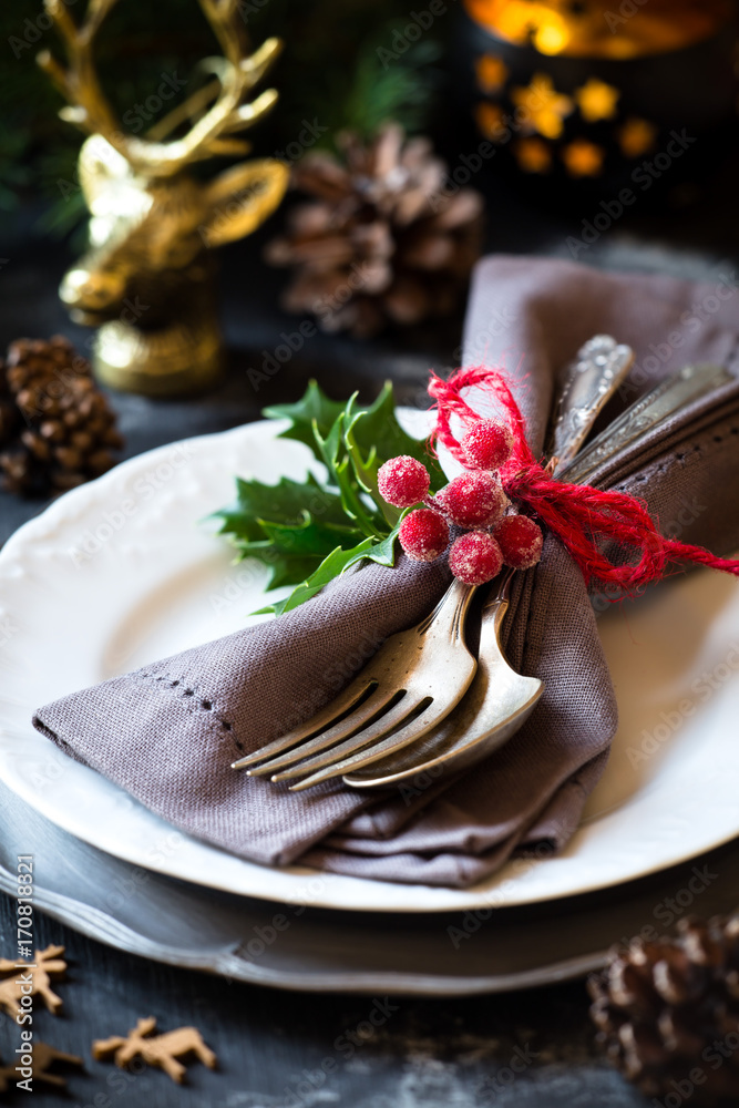 Christmas table place setting with silverware on a plate and festive decorations Christmas table place setting with silverware on a plate and festive decorations