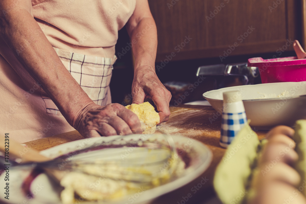 Close up of senior female baker hands kneading dough in kitchen.