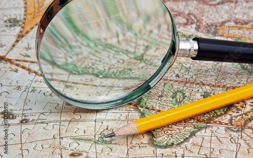 magnifying glass and a pencil on a map