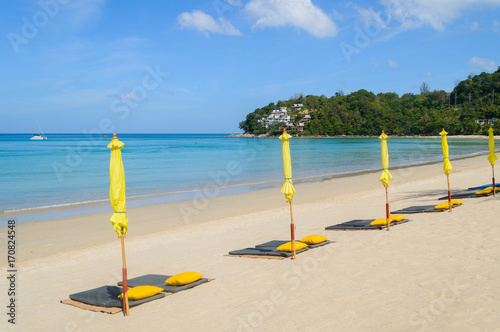 The low season at the seaside. Closed umbrellas on a beach with blue sea photo