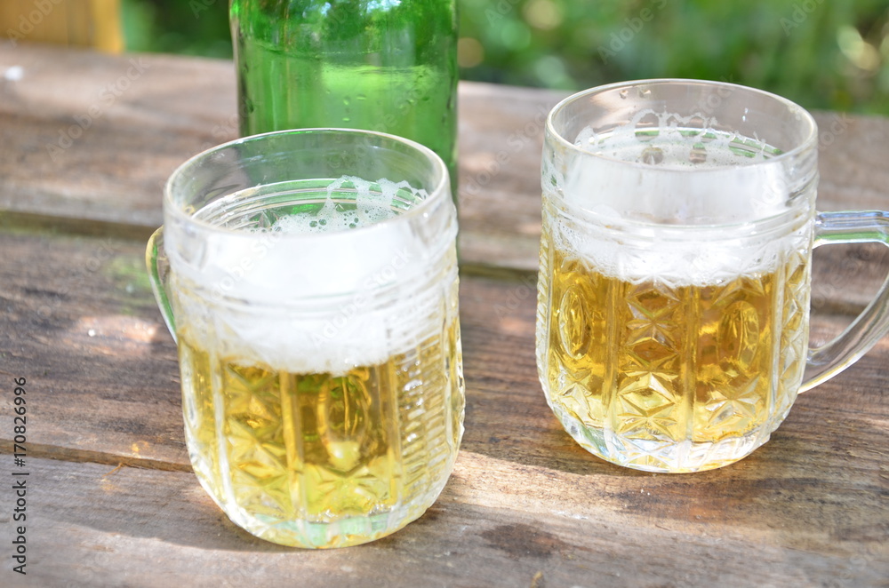 Two Glasses of cider or light beer and bottle on rustic wooden background octobcrfest Two Glasses of cider or light beer and bottle on rustic wooden background octobcrfest