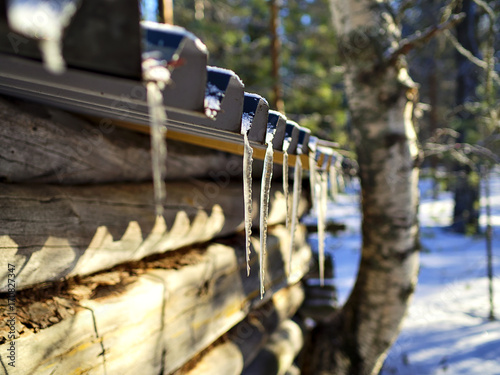 Icicles hanging on the roof of small cottage on sunny winter day.