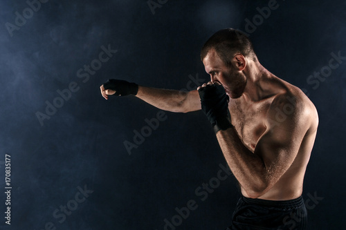The young man kickboxing on black