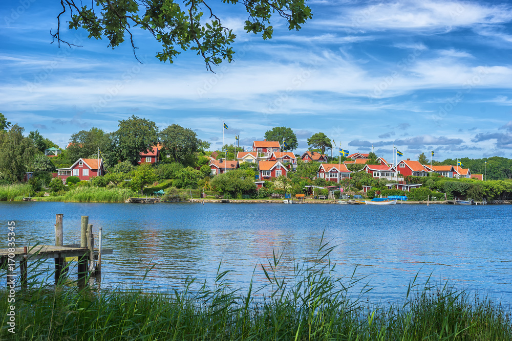 Obraz premium KARLSKRONA, SWEDEN - 2017 July. Typical red Swedish wooden houses with natiaonal flag in the city of Karlskrona