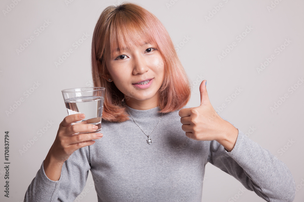 Young Asian woman thumbs up with a glass of drinking water. Young Asian woman thumbs up with a glass of drinking water.