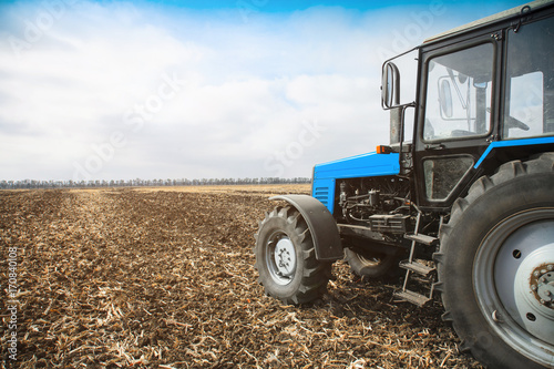Old blue tractor in a empty field. Agricultural machinery, field work.