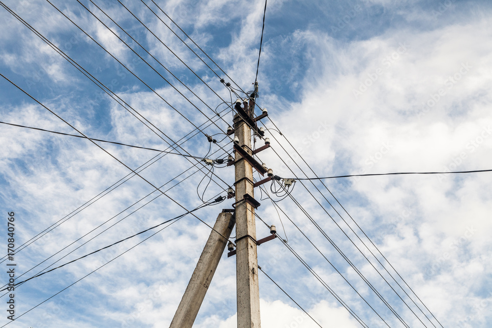 Electric pole with many wires. On blue sky and white clouds background