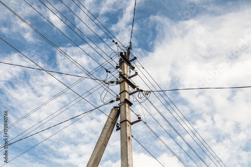 Electric pole with many wires. On blue sky and white clouds background