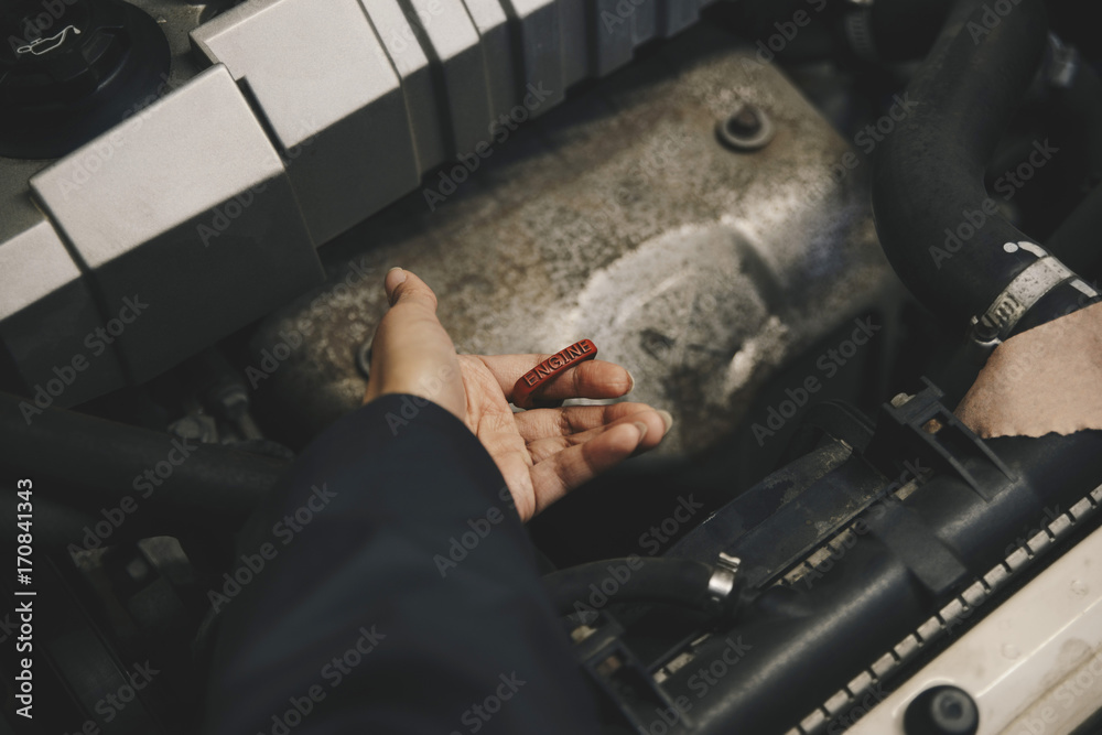 Cropped hand of mechanic examining oil in car engine at auto repair shop Cropped hand of mechanic examining oil in car engine at auto repair shop