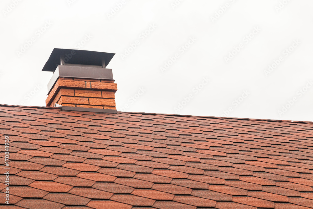 Chimney pipe in red bricks on roof in red shingles. On white background