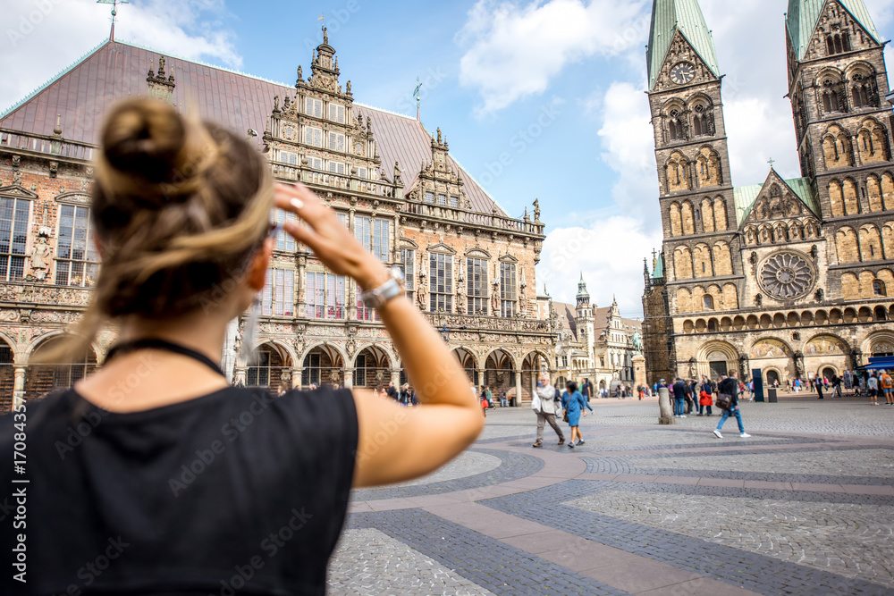 Young woman tourist enjoying great view on the city hall building and church in the centre of Bremen, Hamburg - obrazy, fototapety, plakaty 