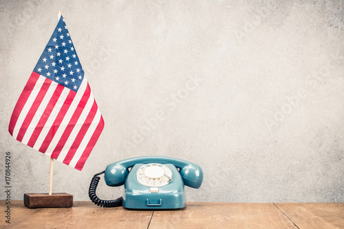 Canvas Print USA flag and retro classic rotary telephone on wooden table front old concrete wall background